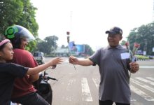 Seorang pekerja membagikan bunga mawar di Kota Tangerang untuk memperingati Hari Buruh. Foto: Antara