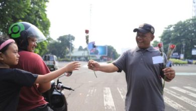 Seorang pekerja membagikan bunga mawar di Kota Tangerang untuk memperingati Hari Buruh. Foto: Antara