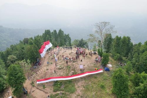 Pendaki gunung dan penggiat pariwisata membentangkan bendera raksasa di Gunung Gedor, Kota Serang. Foto Nana Amdan