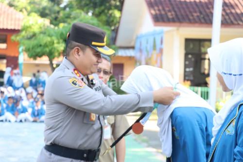 Kapolres Cilegon, AKBP Martua Raja Taripar Laut Sianipar meberikan medali ke siswa SMPN 4 yang berprestasi. Foto Daeng Yusvin