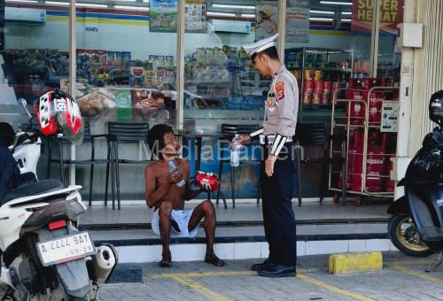 Aipa Kusnandar, anggota Polantas membantu ODGJ menyeberang di Ciruas. Foto: Yono