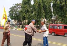 Kasatbinmas Polres Cilegon, Iptu Muhyidin tengah membagikan nasi bungkus dalam Jumat Berkah. Foto Daeng Yusvin