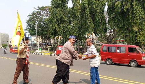 Kasatbinmas Polres Cilegon, Iptu Muhyidin tengah membagikan nasi bungkus dalam Jumat Berkah. Foto Daeng Yusvin