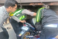 Polisi tengah mengevakuasi pengendara motor yang menabrak truk parkir. Foto Yono