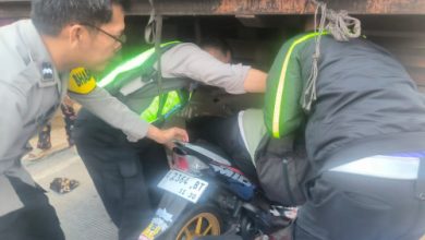 Polisi tengah mengevakuasi pengendara motor yang menabrak truk parkir. Foto Yono