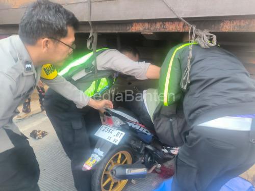 Polisi tengah mengevakuasi pengendara motor yang menabrak truk parkir. Foto Yono