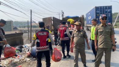 Polsek Cikande ikut membersihkan tumpukan sampah liar di pinggi jalan. Foto Yono