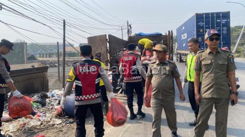 Polsek Cikande ikut membersihkan tumpukan sampah liar di pinggi jalan. Foto Yono