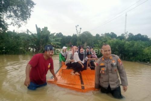 Korban banjir di Binuang diseberangkan dengan rakit oleh petugas Polsek Jawilan. Foto Yono
